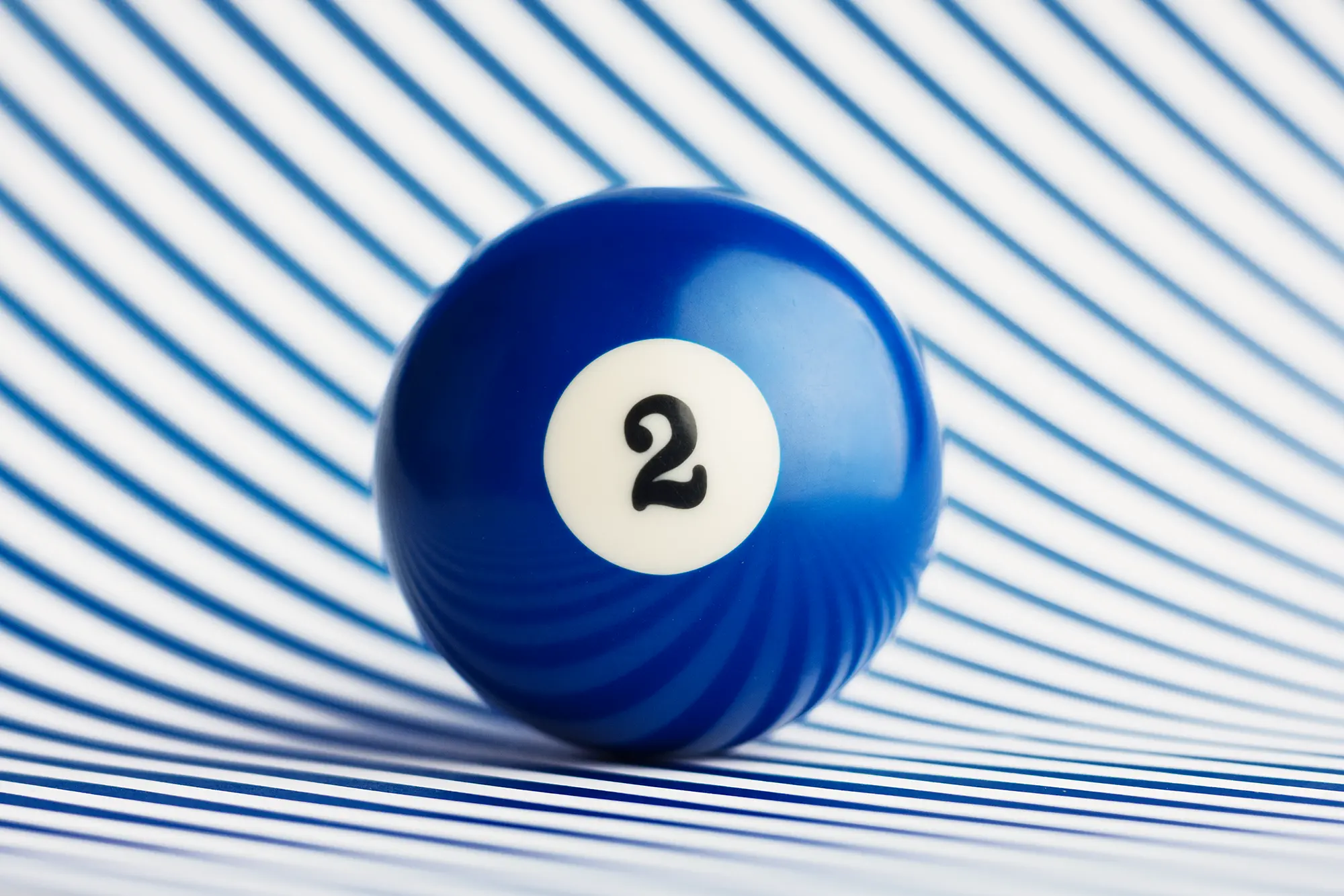 Solid blue billiard ball on a blue and white stripe background.