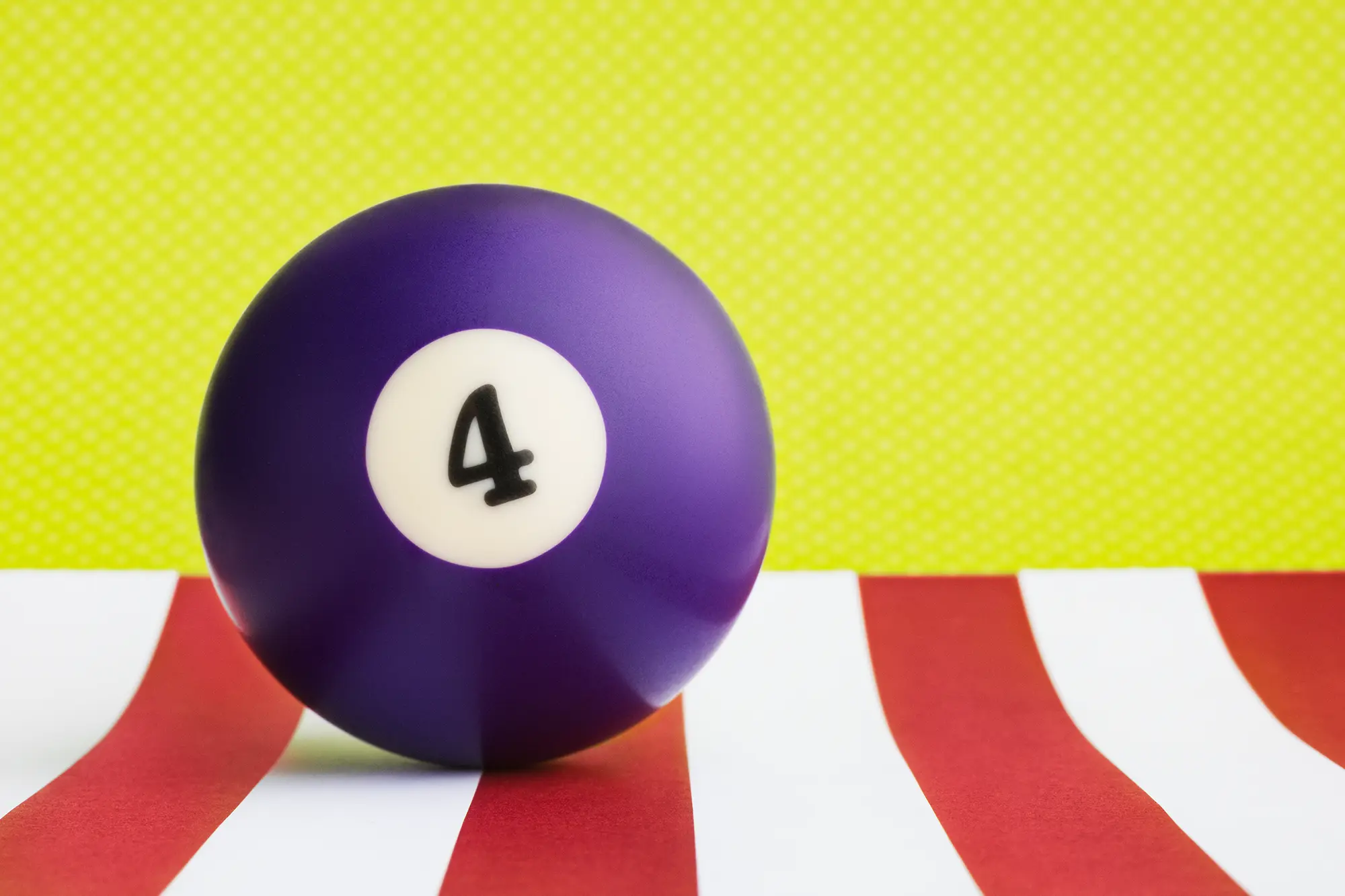Solid purple billiard ball on red and white stripes against a lime green background.