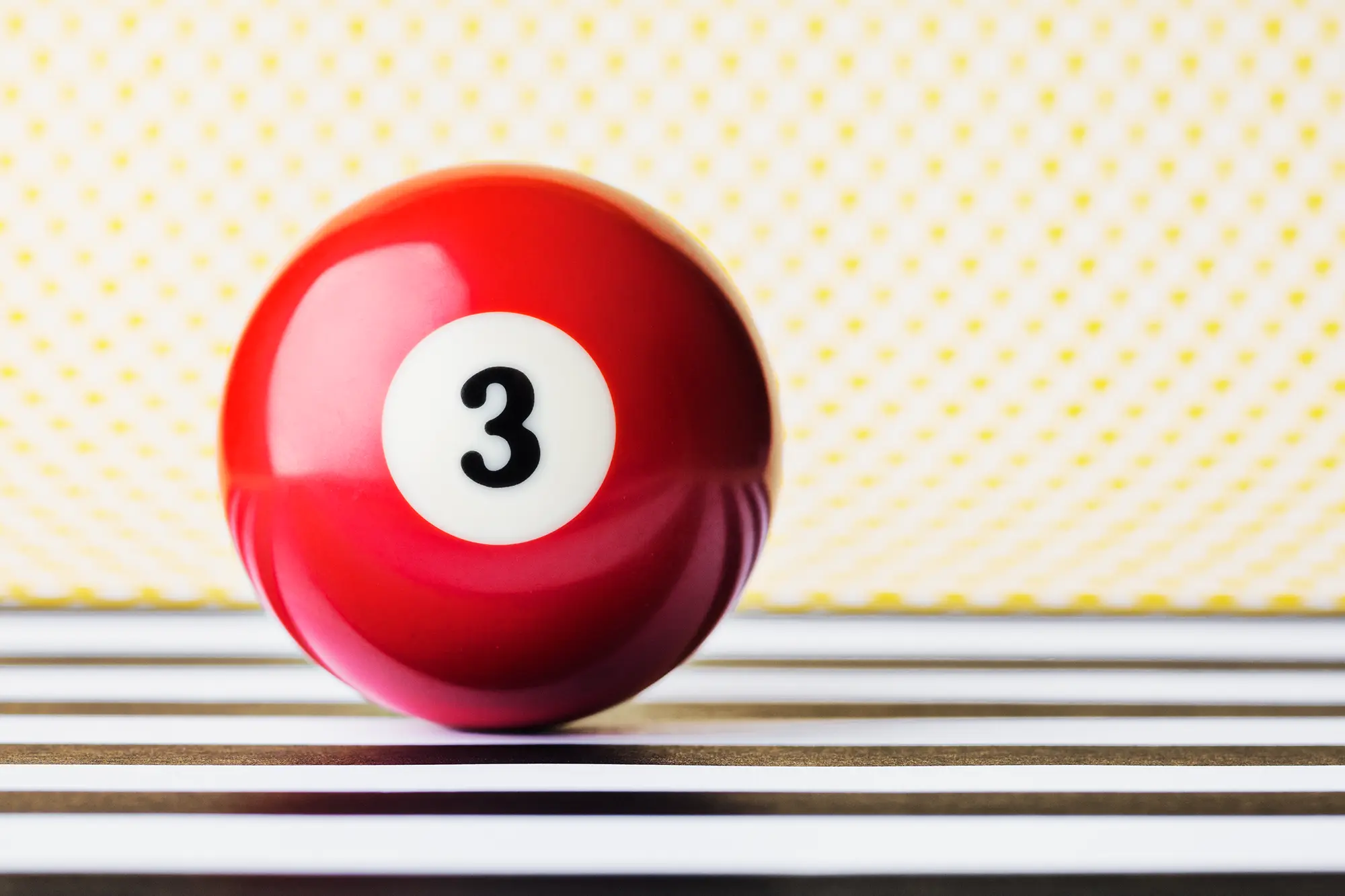 Solid red billiard ball on black stripes with a yellow polka dot background.