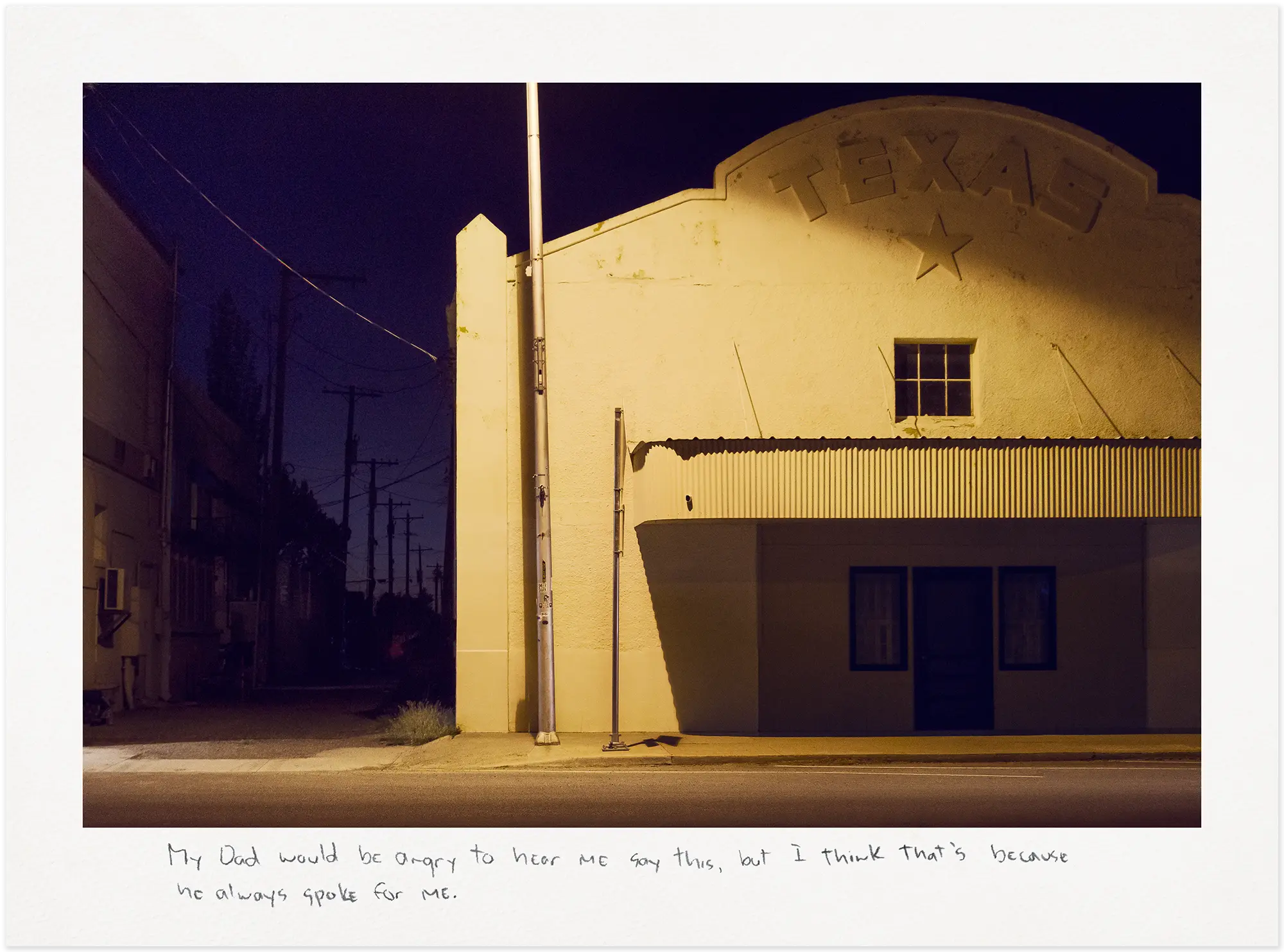 White building with a Texas sign in yellow light at night.