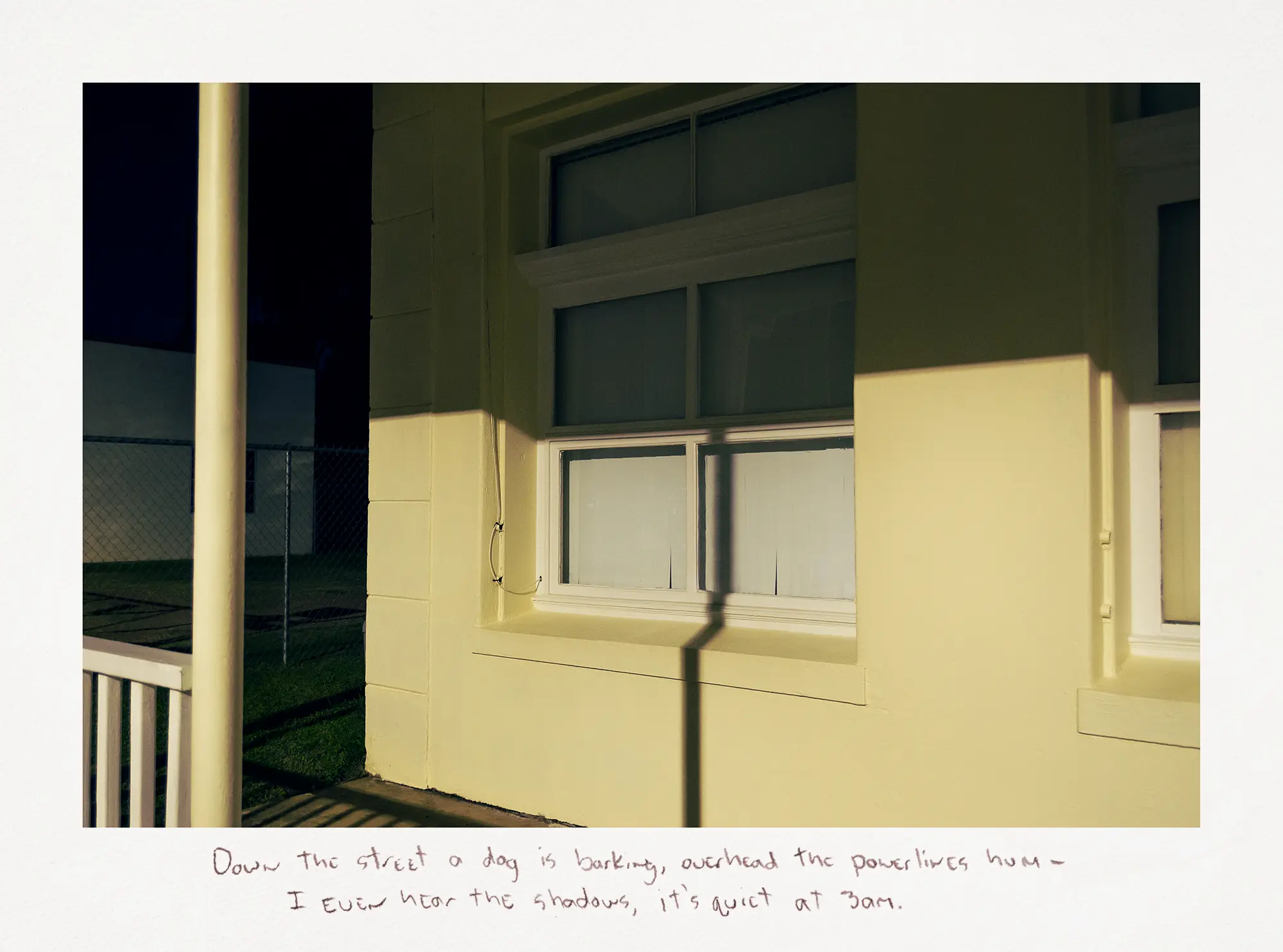 A photograph of a yellow building at night with its front porch and window cast in shadow.